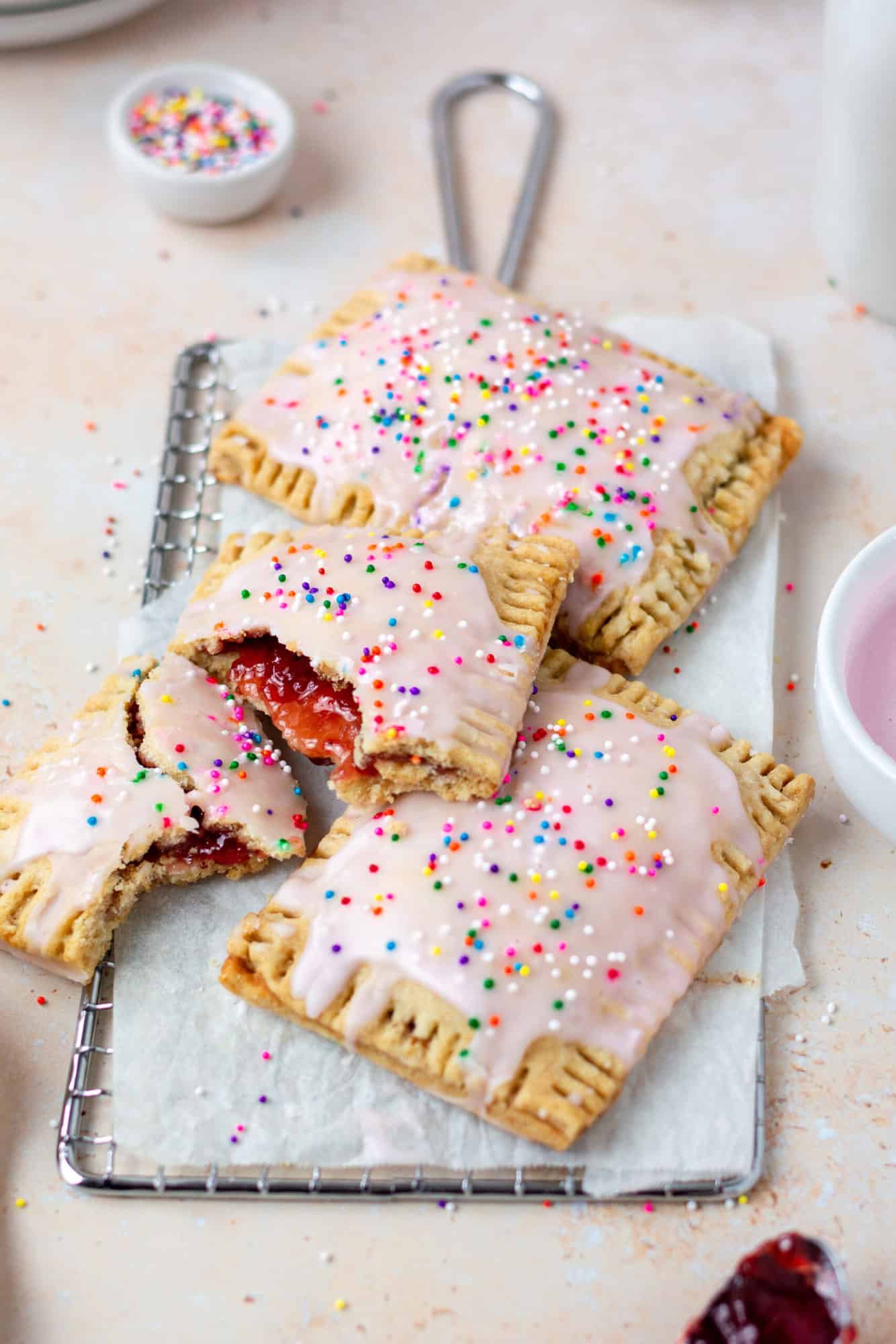 frosted strawberry pop tarts stacked on a cooling rack.
