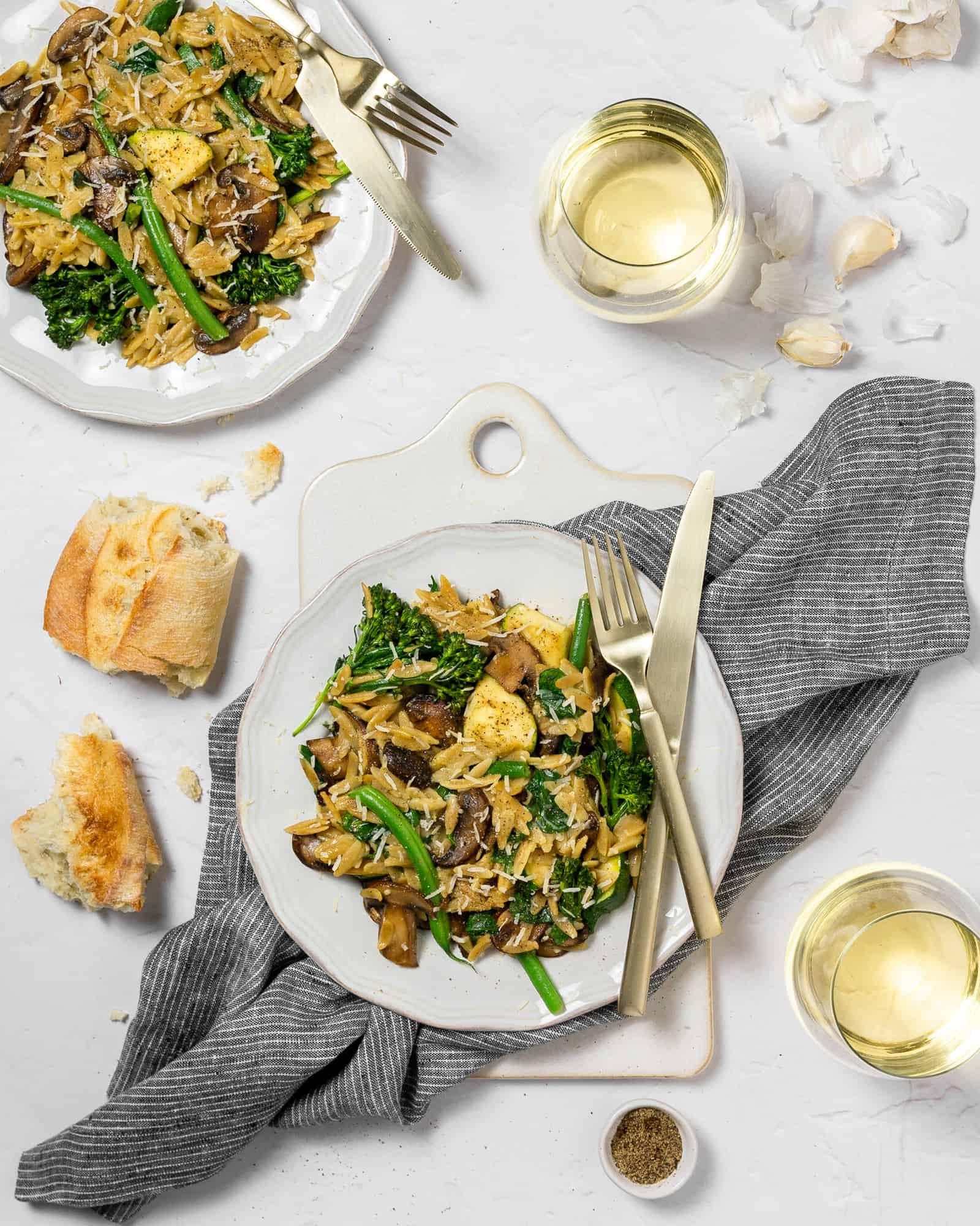pasta primavera on a plate with a baguette and white wine. 