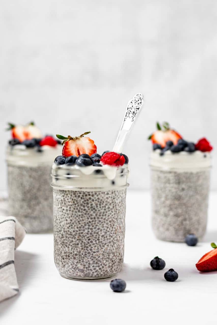 overnight vanilla chia pudding in a mason jar with yogurt and fresh fruit on top