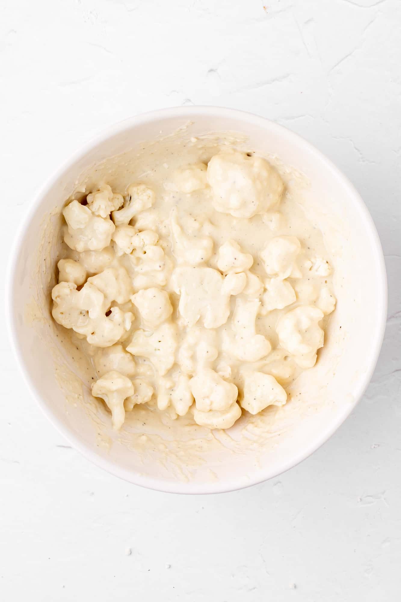 cauliflower mixed into batter in a bowl