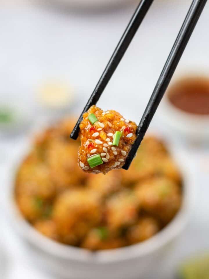 baked cauliflower tossed in bang bang sauce topped with sesame seeds and scallions