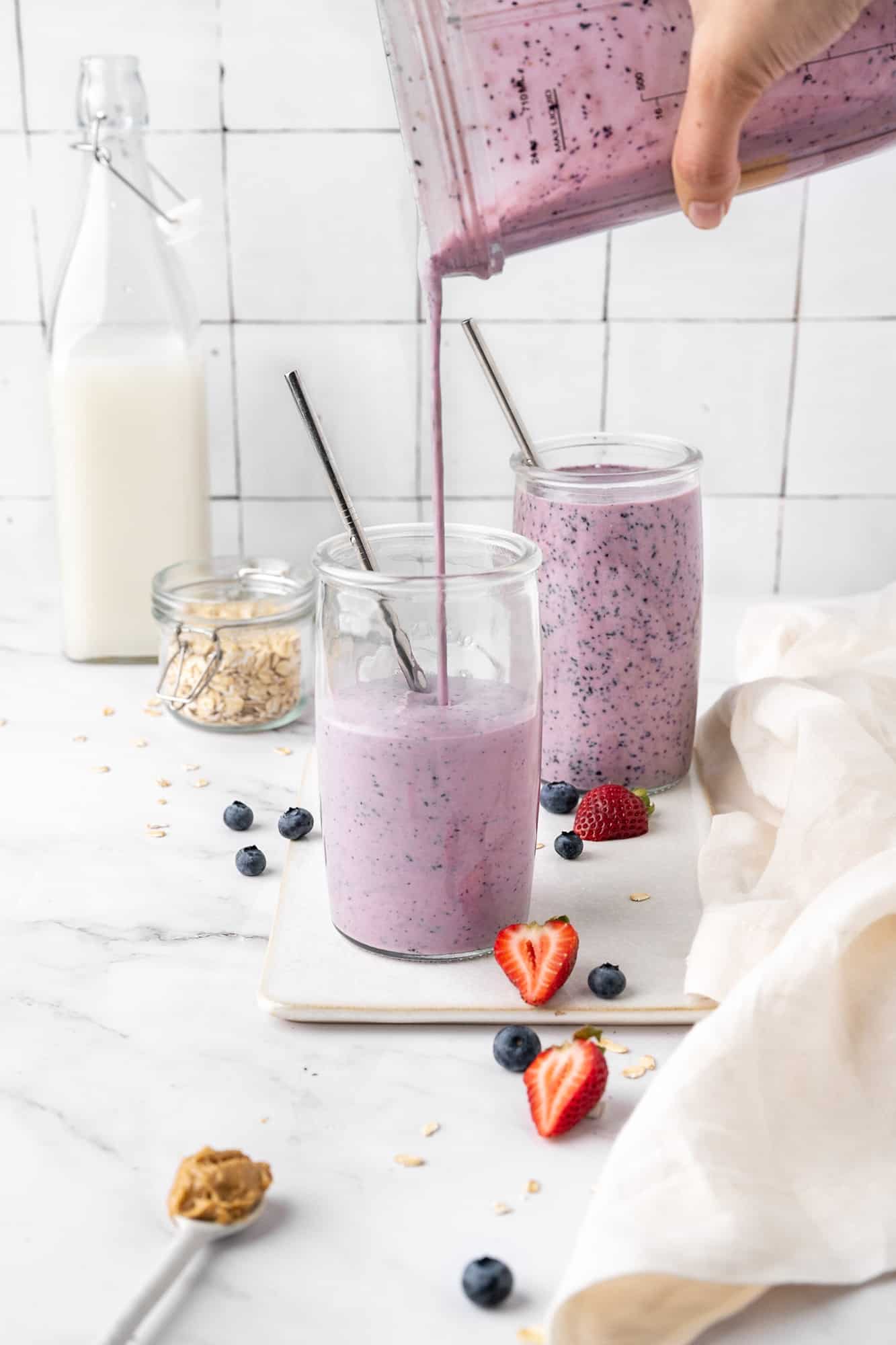 smoothie being poured out of a blender into a cup