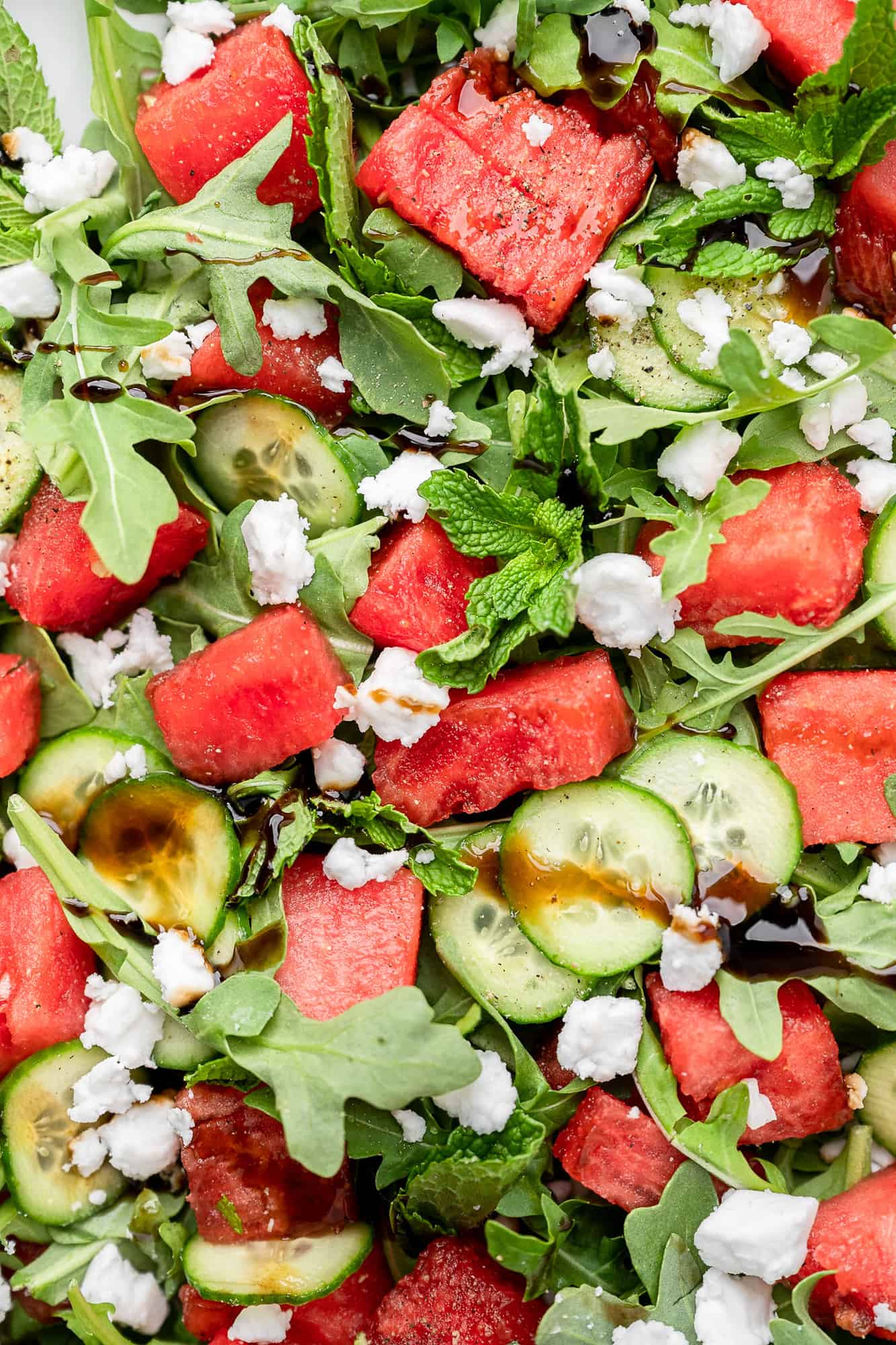 zoomed in photo of watermelon cucumber salad with mint, feta, and arugula
