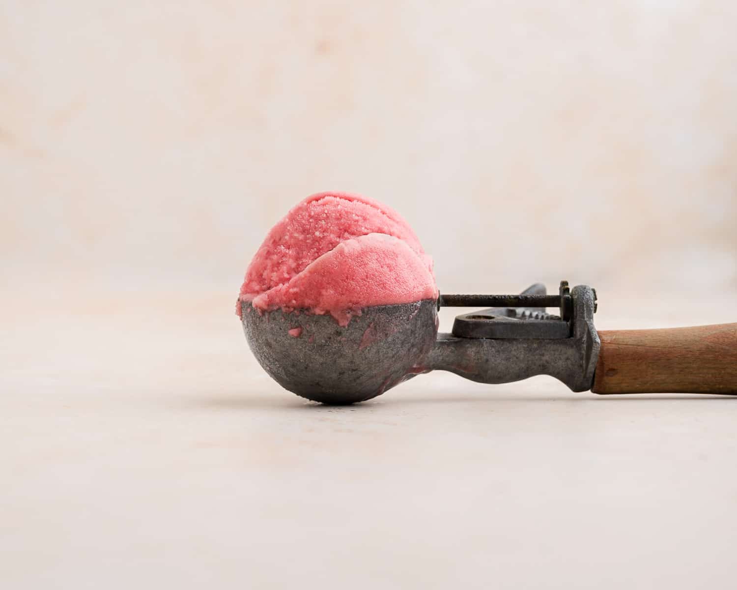 A scoop of raspberry sorbet in an ice cream scooper