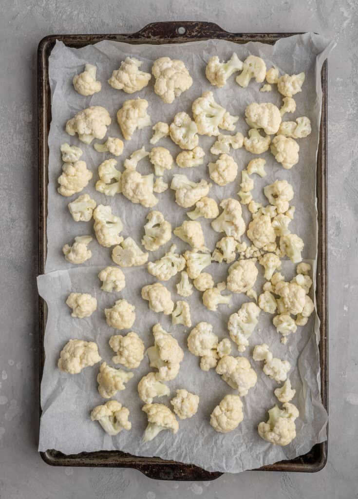 cauliflower on parchment paper on a baking sheet
