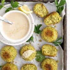 Baked falafel on a baking sheet with tahini sauce