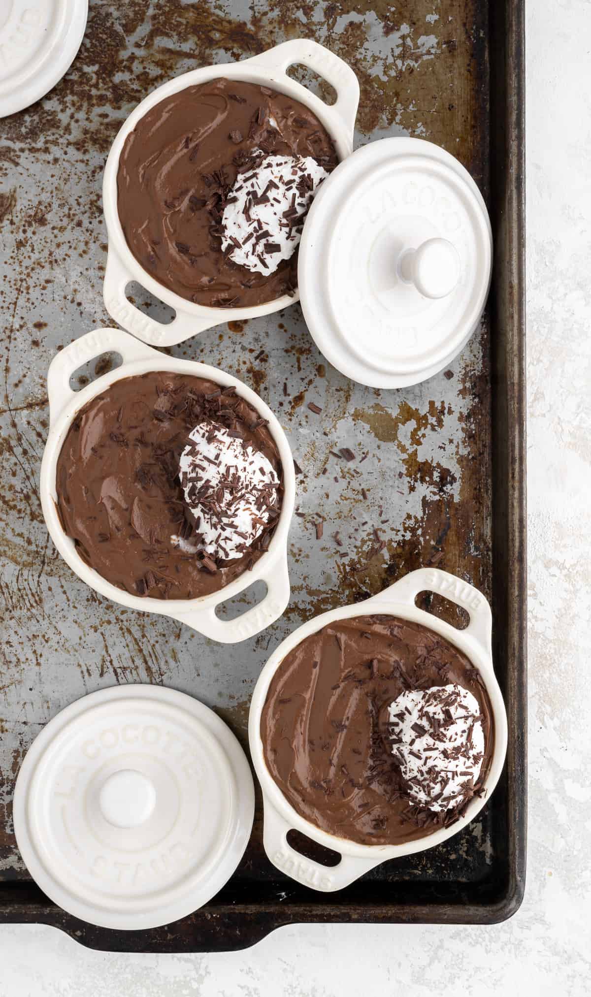 3 ramekins filled with chocolate avocado mousse on top of a baking sheet
