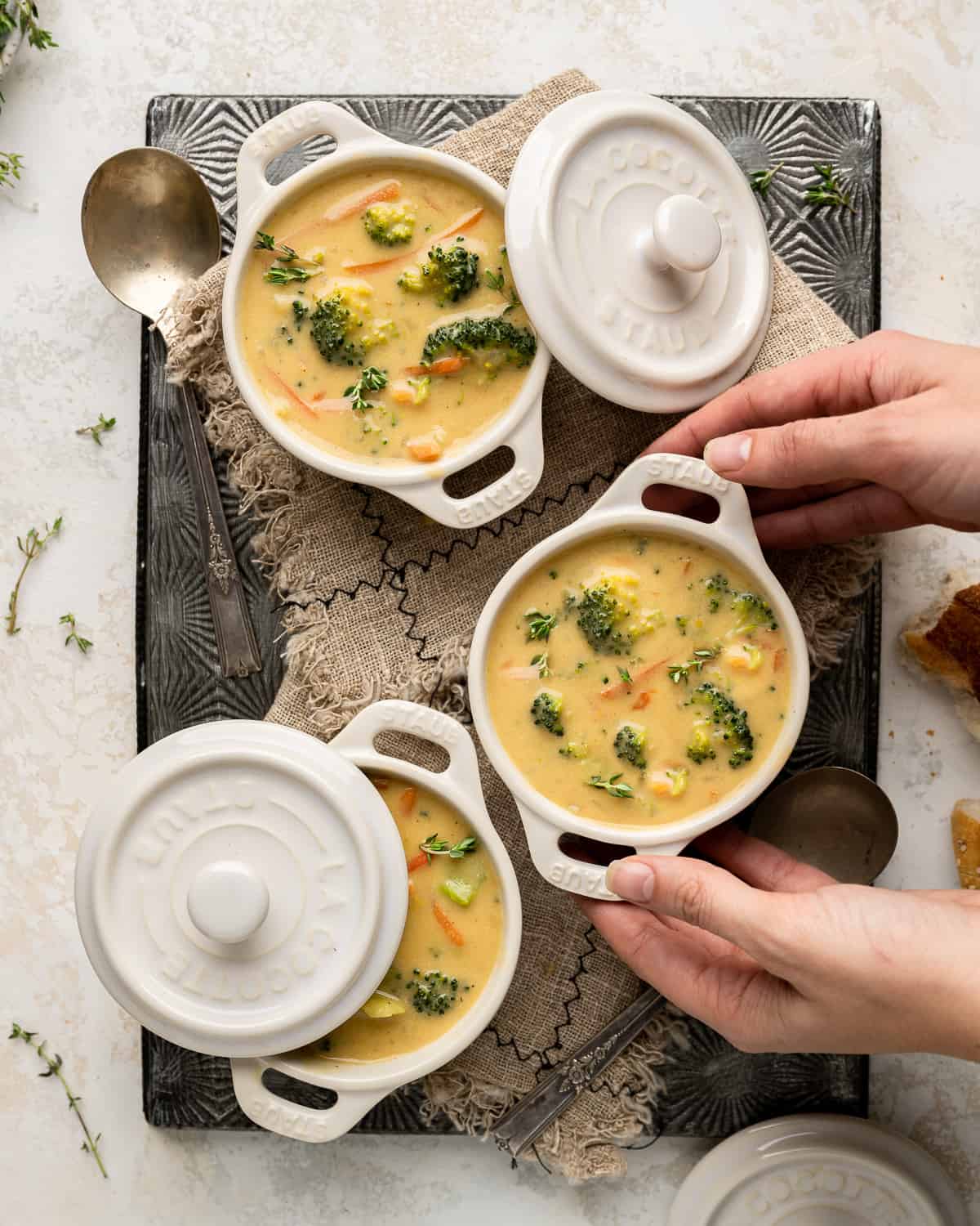 3 ramekins filled with broccoli cheddar soup, 1 being picked up