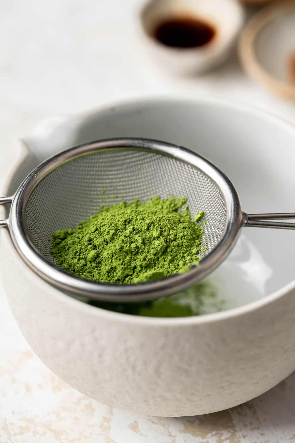 matcha being sifted through a fine mesh strainer.