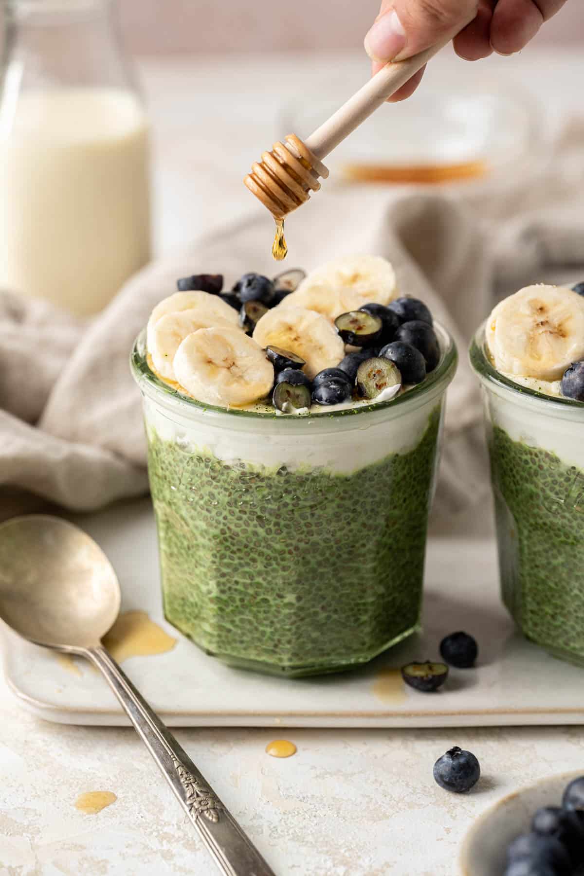 maple syrup being drizzled on top of matcha chia pudding.