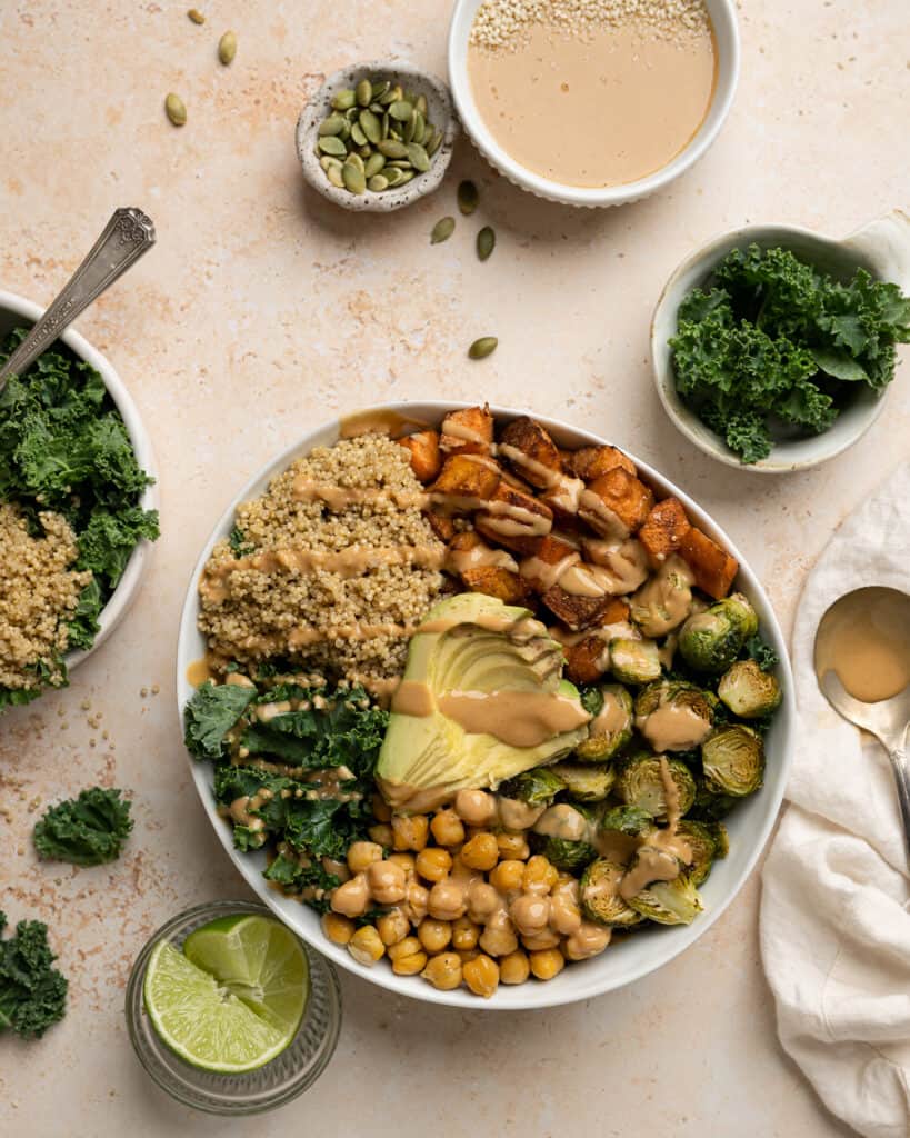 buddha bowl with sweet potatoes, chickpeas, brussel sprouts, kale, quinoa, avocado, and peanut sauce