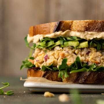 Chickpea tuna salad sandwich topped with avocado, lettuce, sprouts, and hummus.