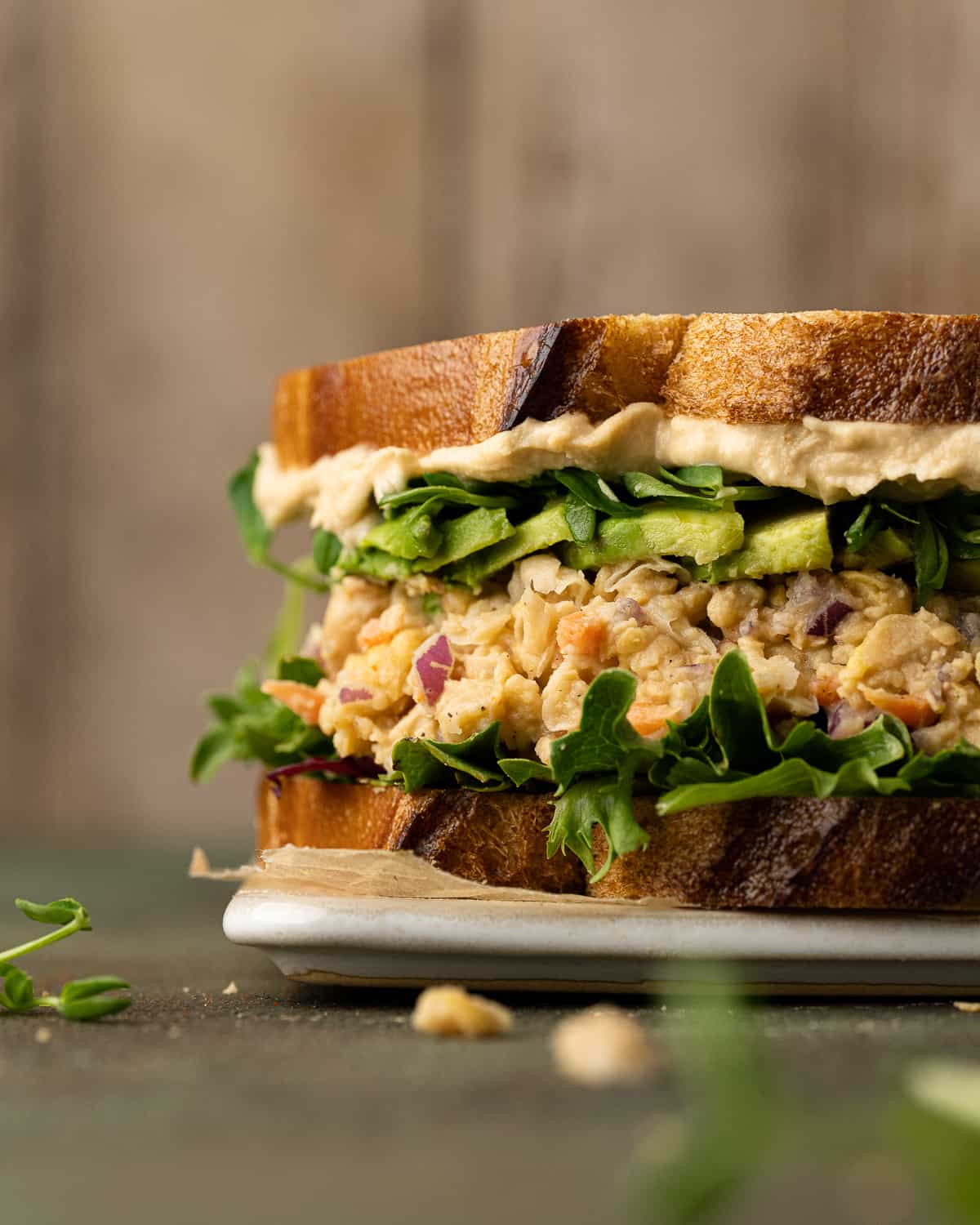 Chickpea tuna salad sandwich topped with avocado, lettuce, sprouts, and hummus.