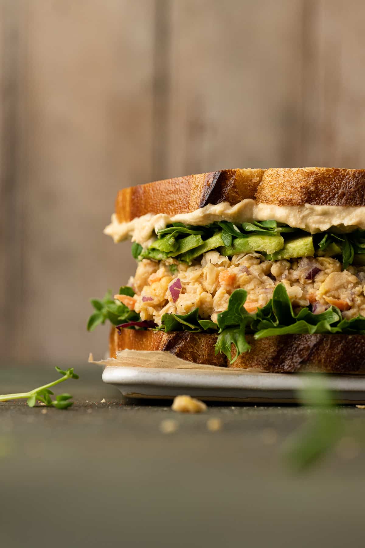 Chickpea tuna salad sandwich topped with avocado, lettuce, sprouts, and hummus.