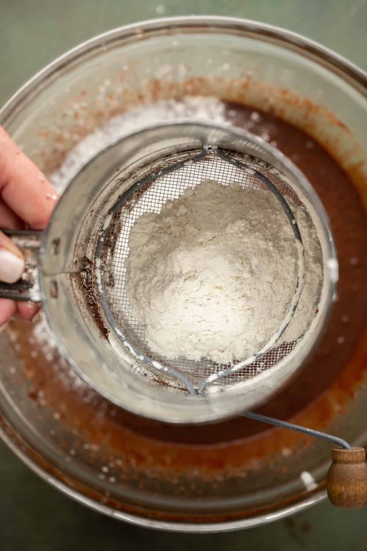 flour being sifted into a bowl.