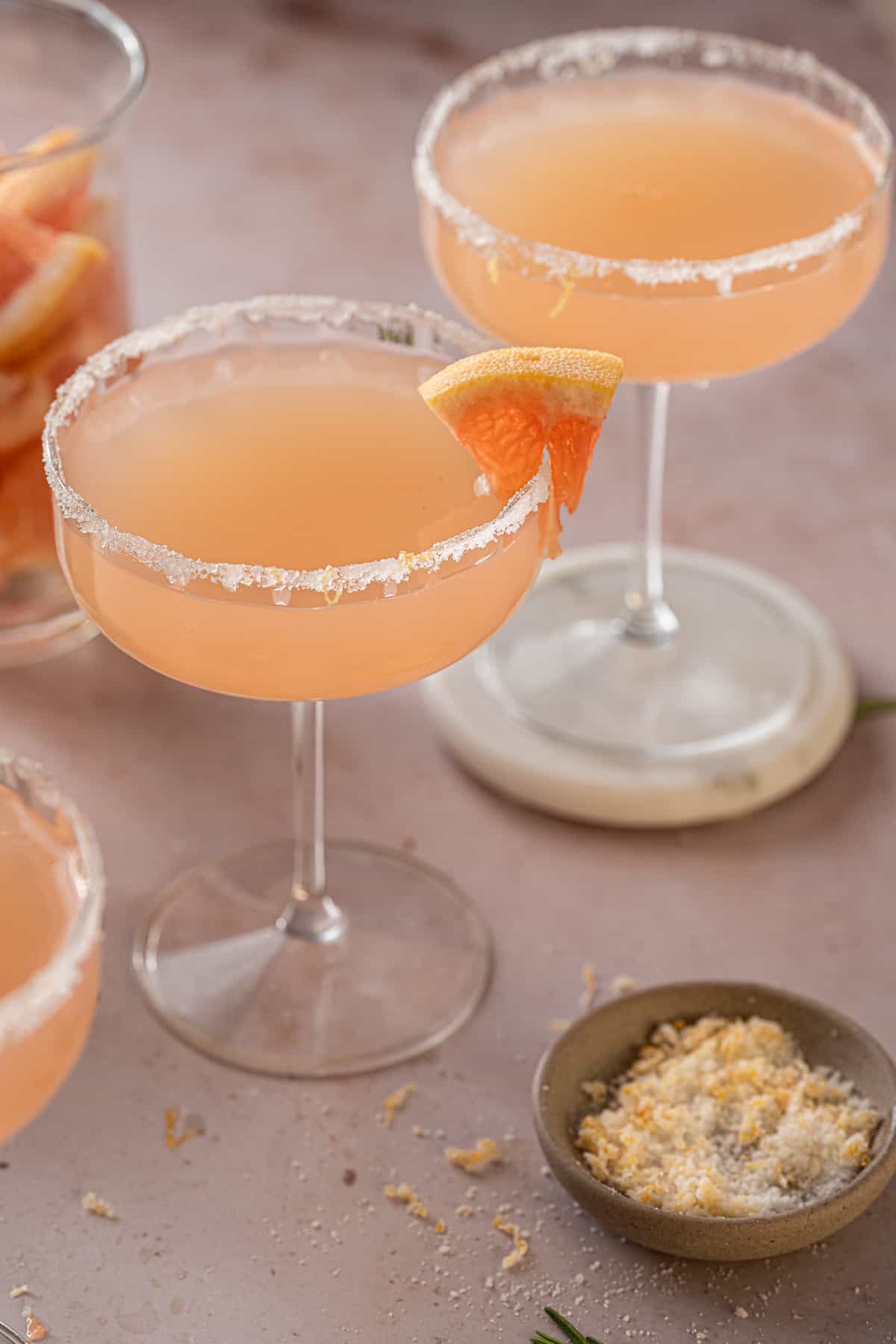 grapefruit gin and prosecco cocktail in coupe glasses with a sugar rim and grapefruit garnish.
