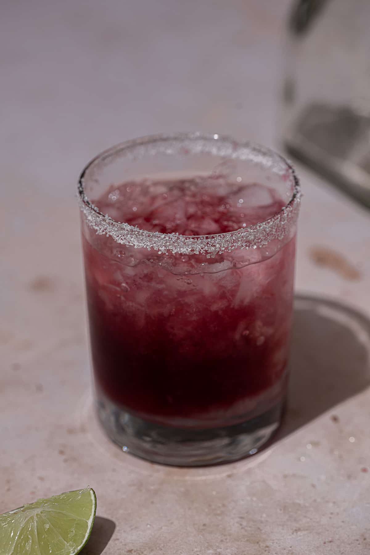 Ice, pomegranate juice, tequila, and triple sec in a cocktail glass.