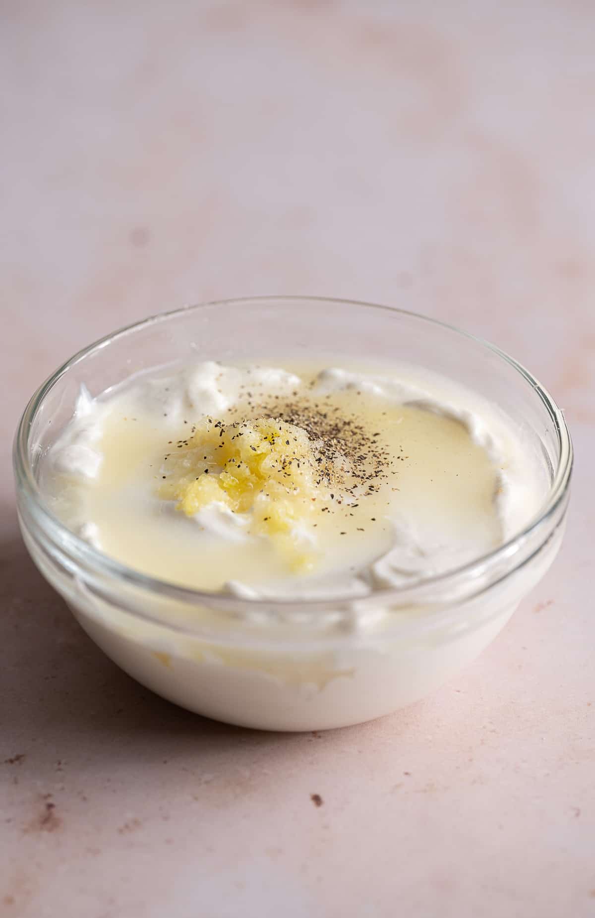 vegan mayo, lemon juice, garlic, salt, and pepper unmixed in a bowl.