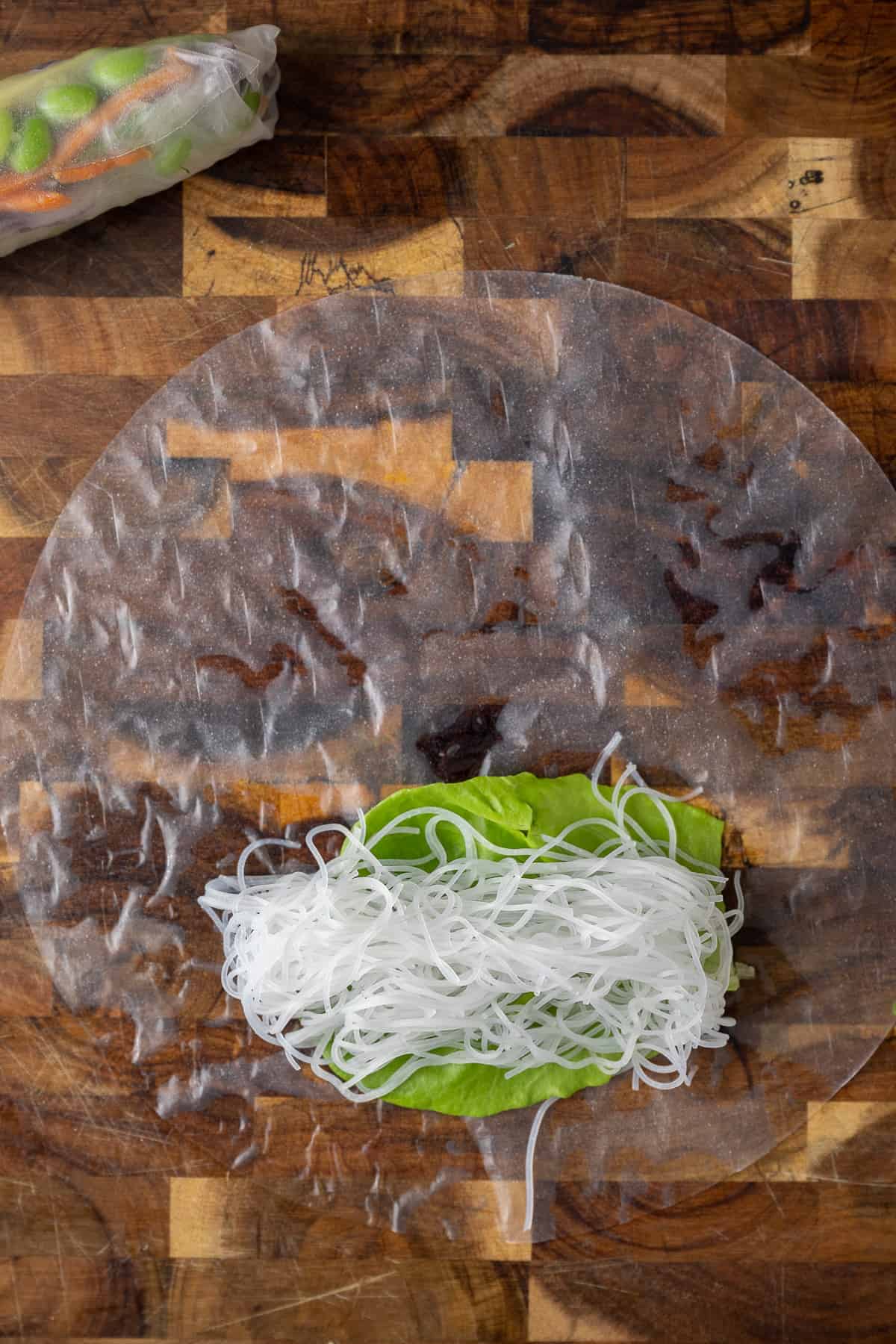 vermicelli noodles on top of a dampened rice paper.