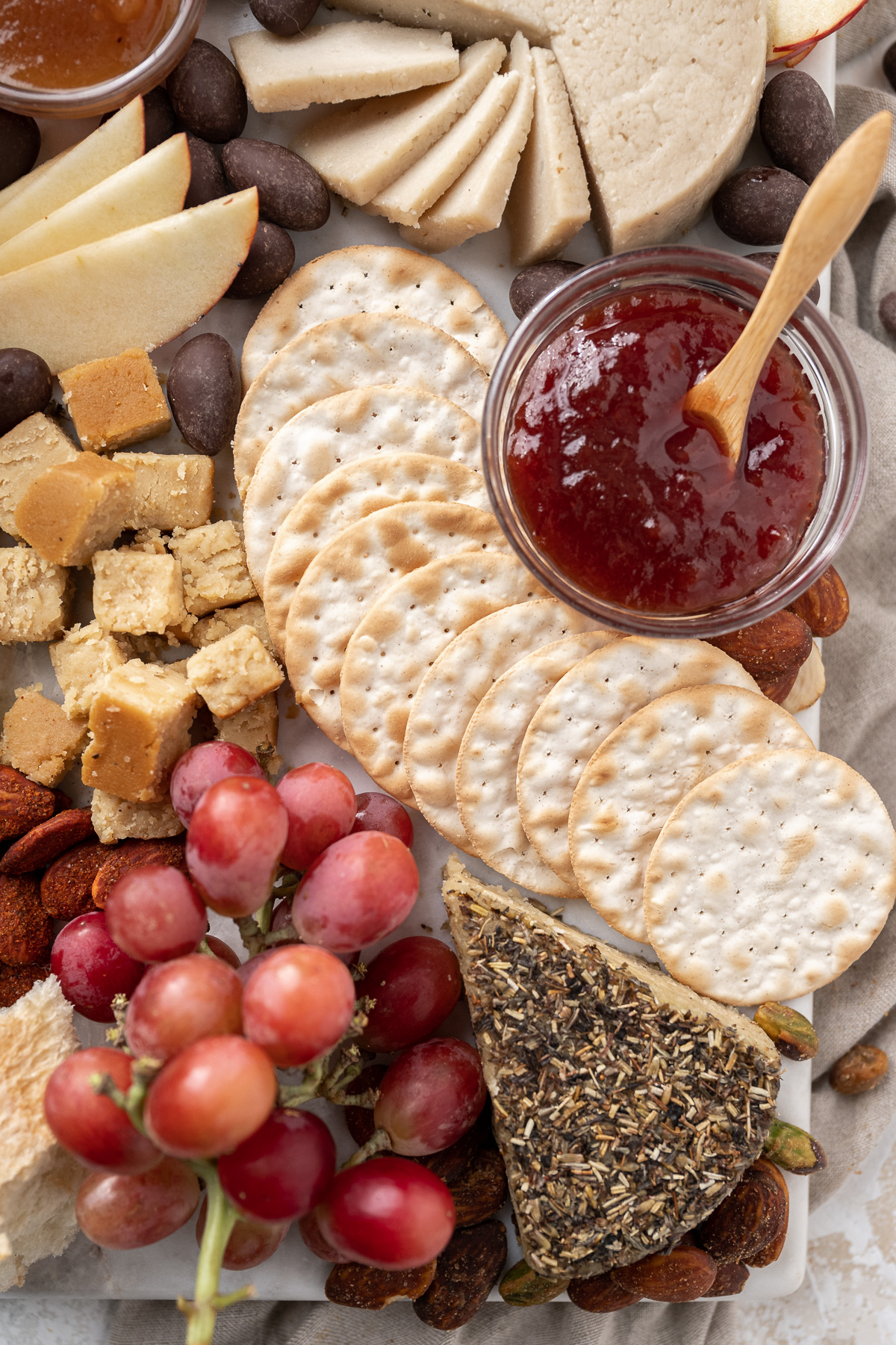 red grapes, vegan cheese, jams and crackers on a platter.