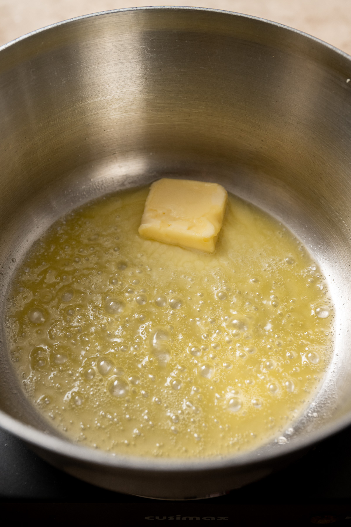 Vegan butter being melted in a stainless steel pot.
