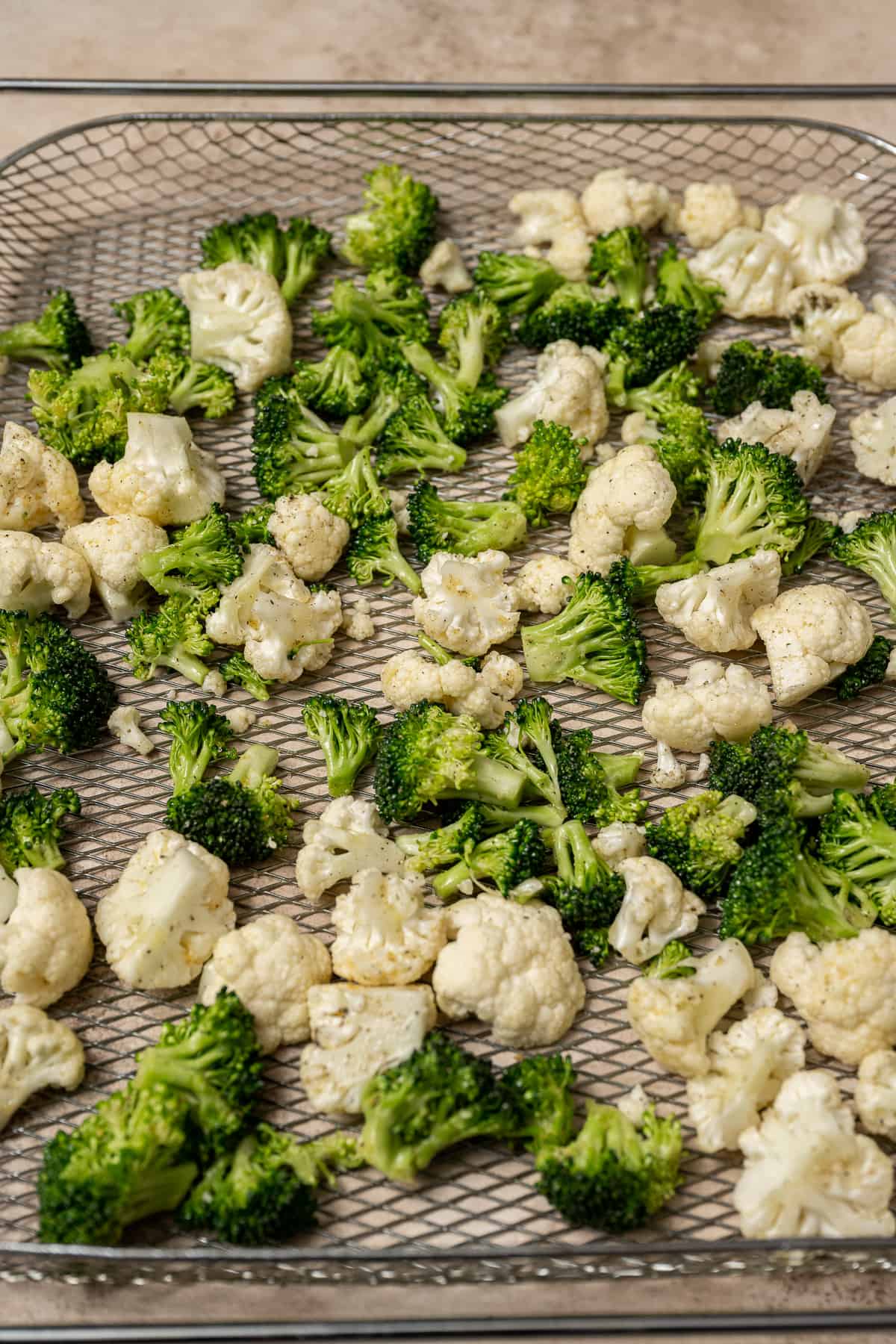 broccoli and cauliflower florets on an air fryer tray.