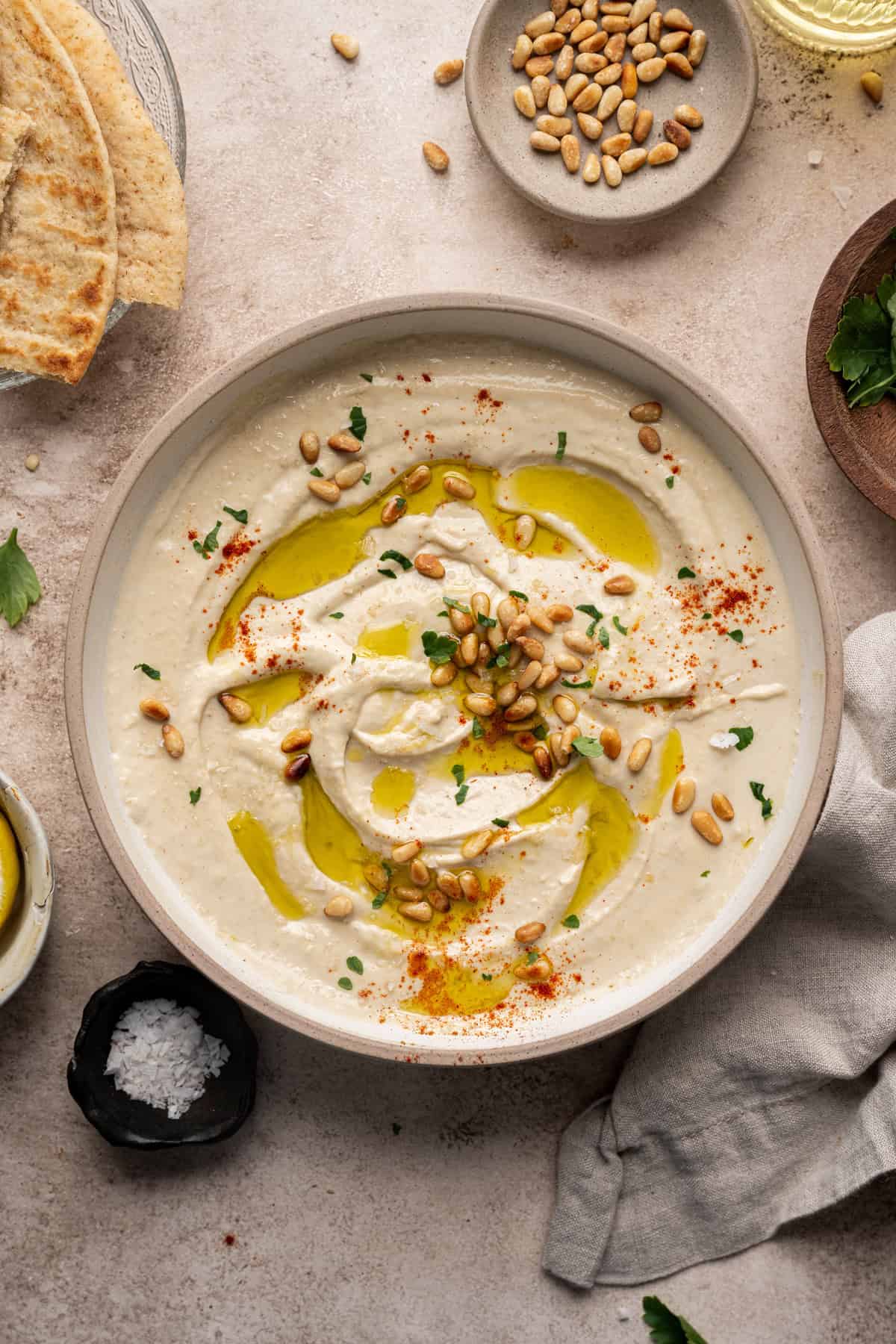 butter bean hummus in a bowl topped with olive oil and pine nuts.