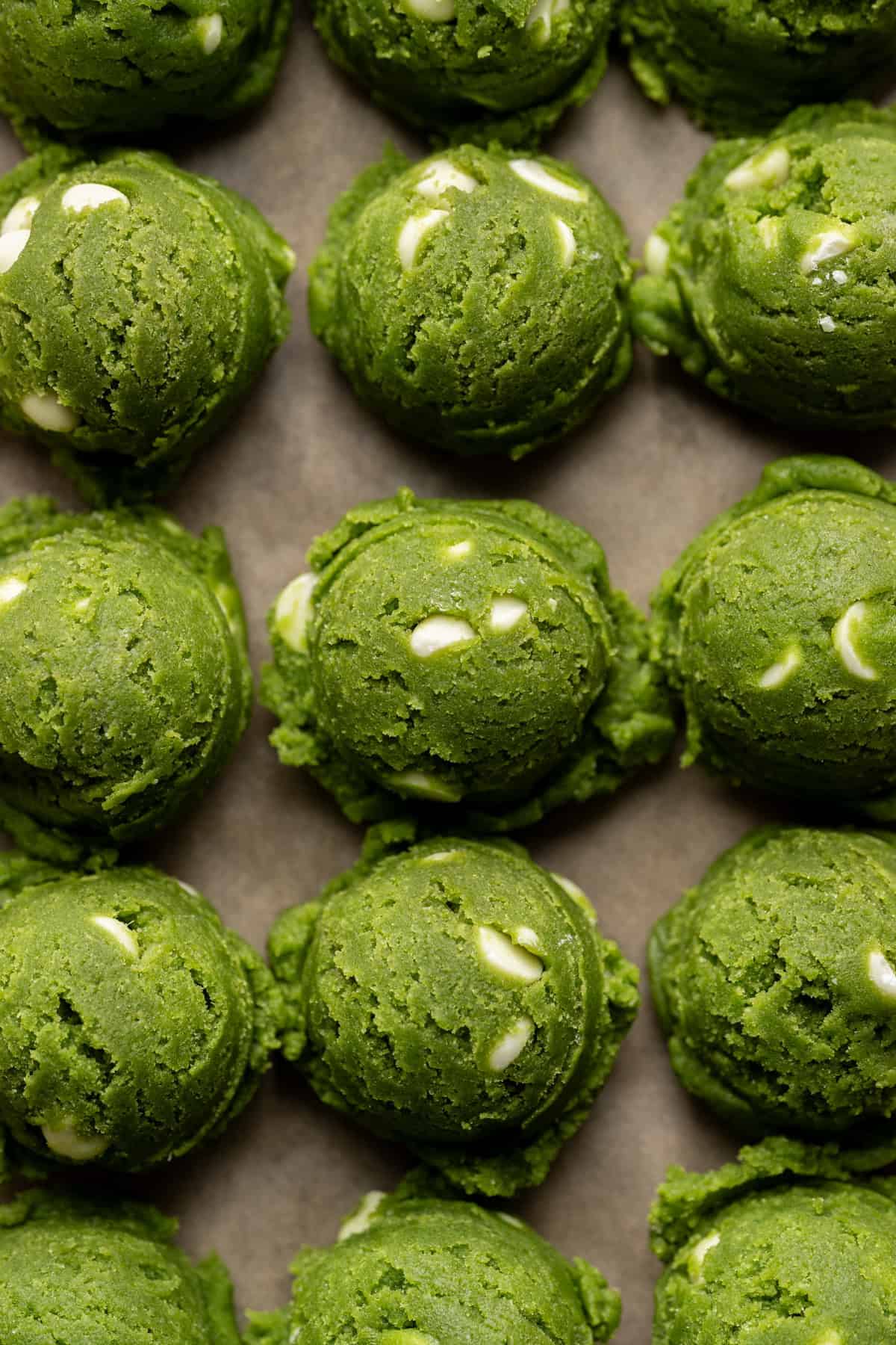 vegan matcha cookie dough balls on a baking sheet.