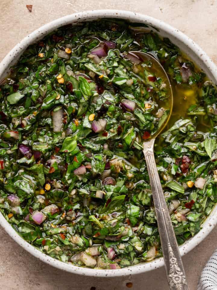 basil chimichurri in a bowl with a spoon in it.